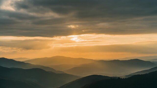 Rayos de sol atravesando nubes sobre un paisaje monta&ntilde;oso al amanecer o atardecer, creando una atm&oacute;sfera serena y dorada.