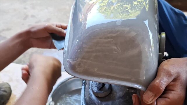 Worker's Hands Wet Sanding Motorcycle Gas Tank for Paint Removal and Body Repair