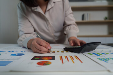 Data Analysis. Businesswoman reviewing financial charts and using calculator.