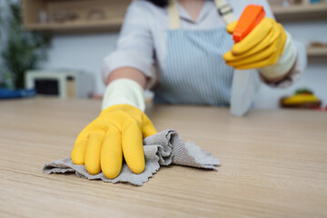Cleaning Routine. Woman using spray to clean table surface.