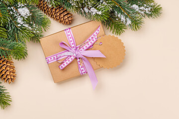 Gift box on snowy fir branches and beige background