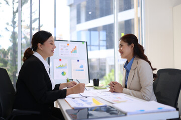 Two businesswoman working with business financial graph data and marketing plan at desk in office, Business concept.