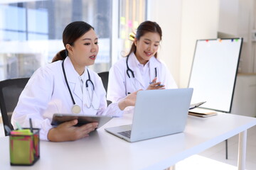 Fototapeta premium Two medical doctors working on laptop with tablet and x-ray film scan in clinic office, Medical technology and Healthcare concept. 