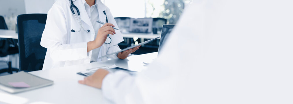 Two medical doctors working on laptop with tablet and a CT scan in clinic office, Body x-ray film, Medical technology and Healthcare concept.