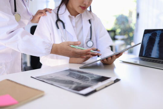 Two medical doctors working on laptop with tablet and a CT scan in clinic office, Body x-ray film, Medical technology and Healthcare concept.  - Powered by Adobe