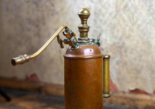 Old brass hand plant sprayer in an abandoned house. Close-up details. Antique gardening tool, retro equipment, collectible decorative object.