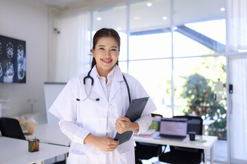 portrait of a smiling female doctor standing with clipboard at hospital , medical and health care.