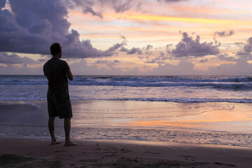 A man in his thirties contemplates the serenity of sunrise on K'gari Fraser Island, QLD.