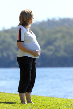 Blonde lady in mid-thirties caressing her pregnant belly.
