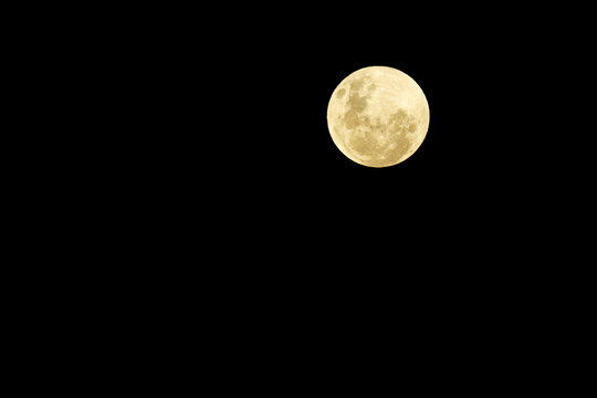 Full moon rising with black sky.