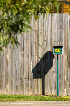 441 green mailbox in front of wooden fence.