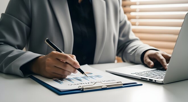 Businessman and businesswoman working on a contract document with a pen and laptop at the office table