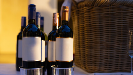 Collection of red wine bottles with blank labels, perfect for mockup. Set against a warm, golden background.