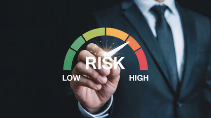 A businessman adjusting a risk meter with low to high indicators in a dark background setting