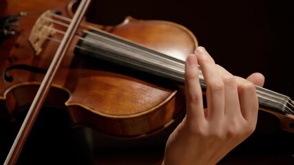 Close-up of a musician's hands playing a classical violin. A violinist demonstrates skillful fingering on the strings of the instrument. Classical music performance concept