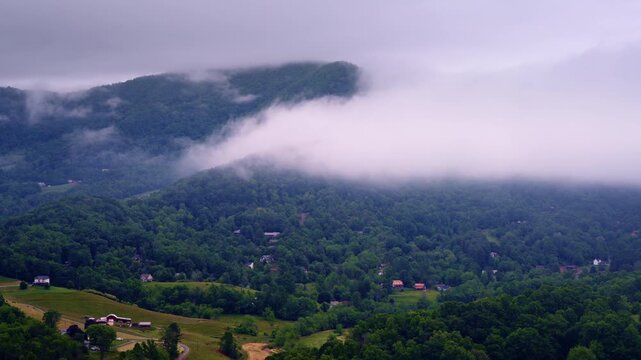 Drone camera floating over a peaceful Smoky Mountain valley covered in fog.