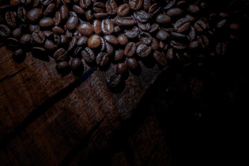 Roasted coffee beans creating a contrast against the dark wooden background with dramatic lighting...