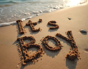 Text It a Boy written in sand on a beach with gentle waves approaching shore. Sunlit ocean background, golden hour light illuminates sandy message. Joyful announcement of new male child birth.