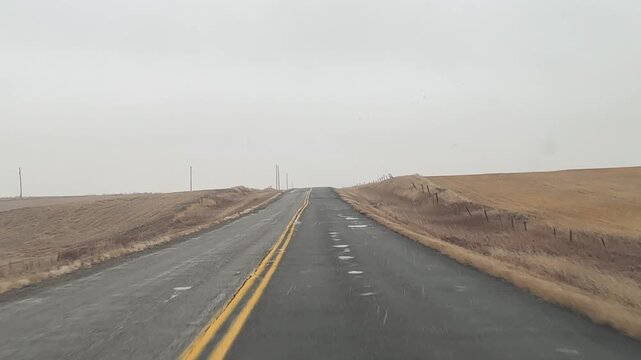 POV of winter roads with compact snow and frost buildup along the edges as the vehicle continues forward. Alberta Canada.
