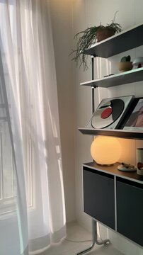 White curtain gently swaying in the breeze by the window &ndash; calm cozy home interior with soft natural light
