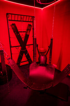 Sex swing in red light. BDSM equipment.