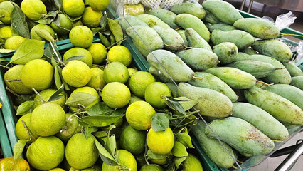 Nature's Bounty: A vibrant display of Fresh green limes and unripe mangoes arranged in baskets, showcasing vibrant colors and natural textures in supermarket.