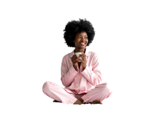 A person with dark skin sits cross-legged, wearing pink pajamas, holding a mug, and gazing thoughtfully upward