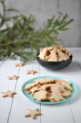 Homemade Christmas cookies shaped like trees and stars on a turquoise plate, with festive rustic decor and soft natural light creating a cozy holiday atmosphere.