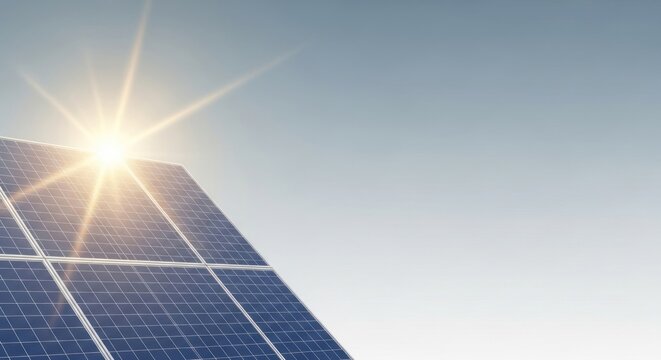 A solar panel array against a clear blue sky with the sun shining brightly.