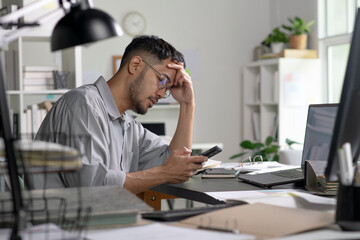 Businessman looking stressed while using phone, Businessman working at office feels overworked and burnout