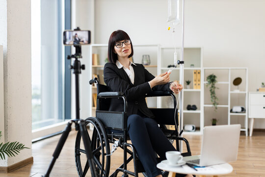 Caucasian woman seated in wheelchair under intravenous therapy shares work-life balance advice on camera.