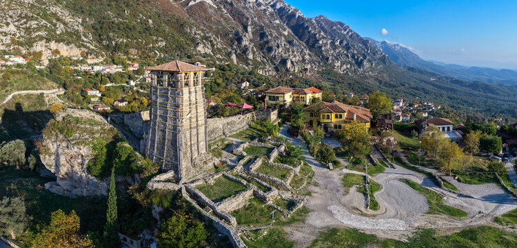 Aerial view of Krujë Castle tower in Albania and ruins on a rocky hilltop with mountain scenery and hillside houses in afternoon light. - Powered by Adobe