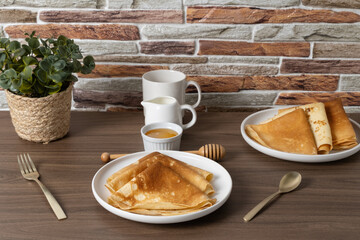 Delicious golden crepes served with honey and sauce on a rustic wooden table in a cozy setting