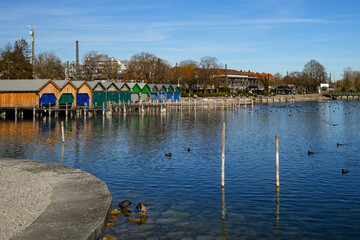 The lakeside promenade with colorful boathouses on Lake Starnberg on a bright, sunny autumn day