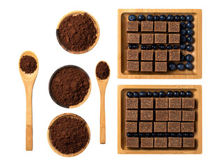 Overhead shot of cocoa powder, spoons, berry squares, and blueberries on bamboo trays
