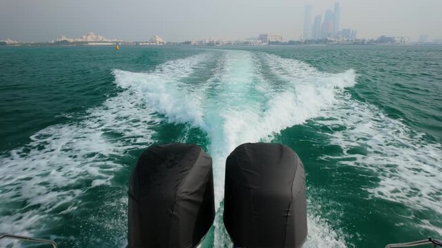 The Wake From Twin Motors On A Boat Cruising The Arabian Sea With The Abu Dhabi Skyline On The Horizon.