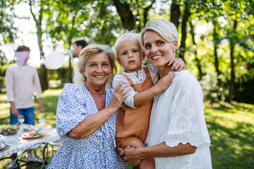 Smiling grandmother talking with her daughter, holding grandchild, family gathering.