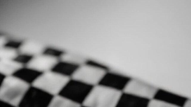 A close-up, blurred shot of a black and white checkered pattern waving
