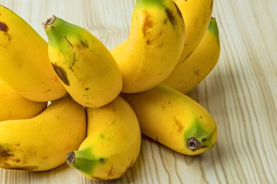 Bunch of ripe yellow bananas on a light wood surface