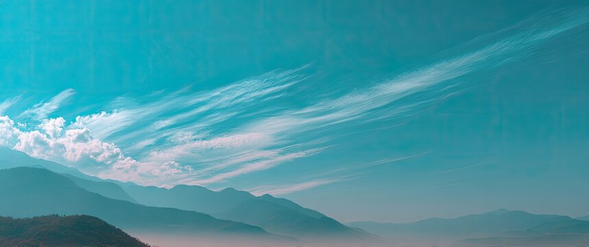 Turquoise sky with wispy clouds over hazy mountain range