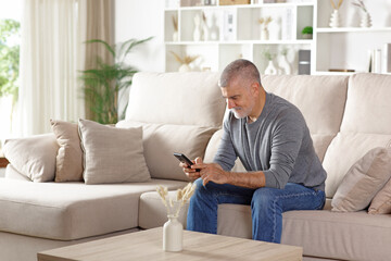 Happy senior man using cell phone at home