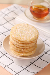 Crispy Rice Crackers Snacks Stacked on Plate with Tea Cup Background