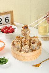 Traditional Handmade Siu Mai Dumplings in Bamboo Steamer with Chopsticks and Tea Service