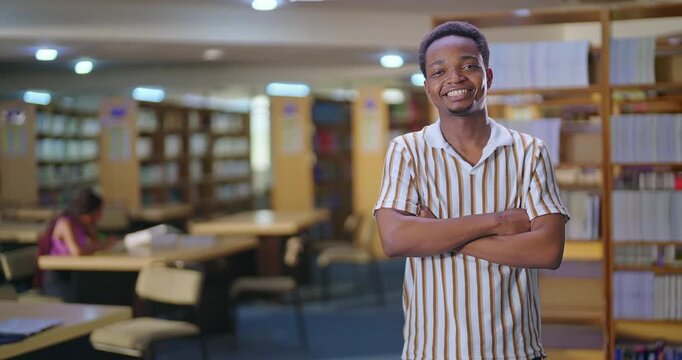 African young adult gen z happy man male student standing proud fold hand look camera indoor library ready for exam smiling smart boy  guy cross arms staring cam do pose enjoy day time college place