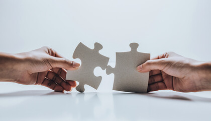 Two hands connecting puzzle pieces, symbolizing creativity, innovation, and problem solving in modern business teamwork concept photography