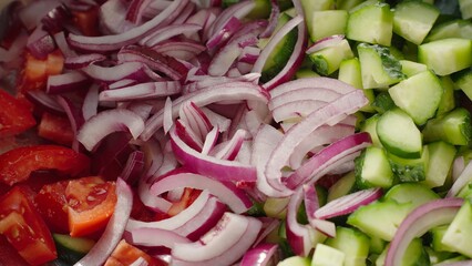 Sliced red onions, diced cucumbers, and chopped tomatoes combine in a colorful and healthy salad. Macro background fresh ingredients ready to be tossed and enjoyed