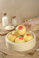 Traditional Chinese Steamed Buns in Bamboo Steamer Basket with Hand Picking Asian Dumpling Food