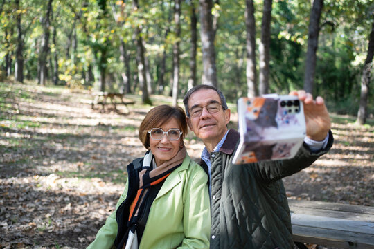 Senior couple taking selfie using smartphone in autumn park