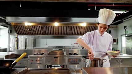 Young culinary student in a white chef uniform plating hot pasta from a steaming pot in a professional kitchen, demonstrating practical cooking skills during chef training at a culinary institute.