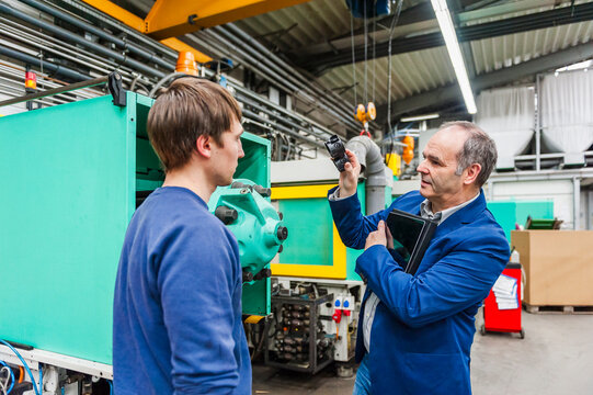 Engineer and machine operator consulting in plastics production hall